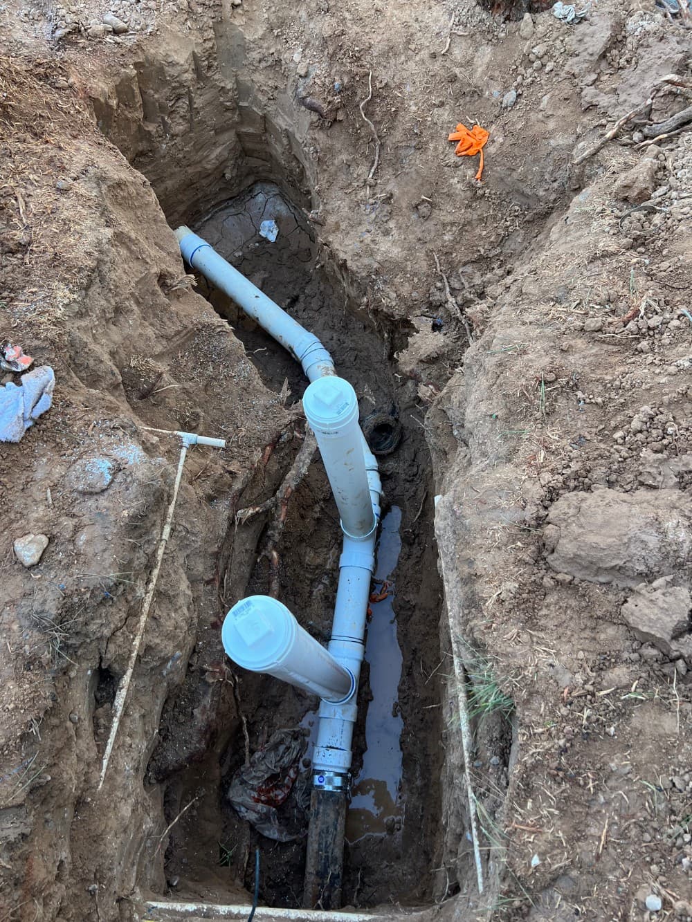 New PVC sewer line laid in an open trench during a full sewer replacement by Omnia Plumbing.