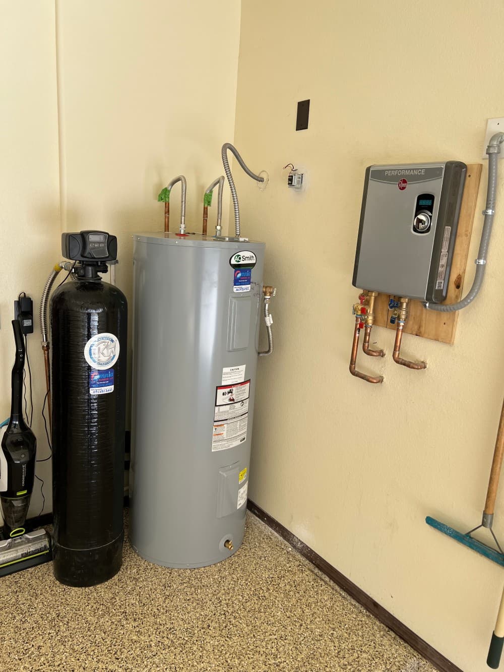 Whole-home water softener installed alongside a residential tank water heater by Omnia Plumbing.